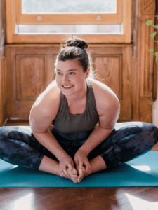 Young woman smiling while stretching on a yoga mat